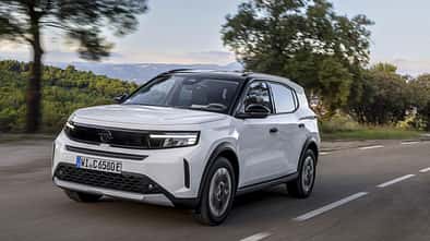 Opel Frontera Electric Extended Range in weiss mit schwarzem dach, frontansicht schraeg, fahrend auf landstrasse