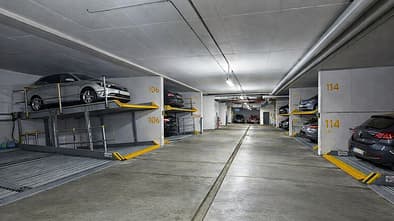 Duplex-Parksystem in einer Tiefgarage mit geparkten Fahrzeugen auf zwei Ebenen und nummerierten Stellplaetzen