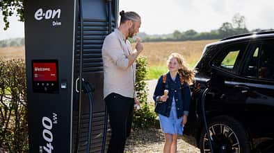 E.ON-Drive-Ladesäule mit einem Elektroauto während eines Ladevorgangs an einem öffentlichen Standort im ländlichen Raum.