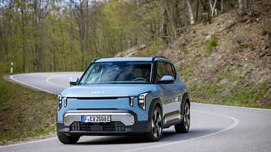 Kia EV2 in Frontansicht bei Fahrt durch eine Kurve auf Landstraße