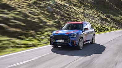 Frontansicht des MINI Countryman JCW auf einer Bergstraße in den Alpen.