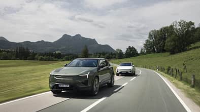 Zwei Polestar 3 Performance fahren auf einer Landstraße durch eine hügelige Landschaft.