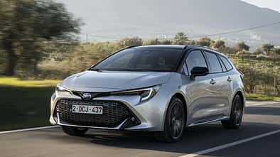 Toyota Corolla Touring Sports 2.0 Hybrid in Silber während der Fahrt, Frontansicht auf einer Landstraße.