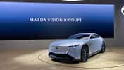 Mazda Vision X-Coupé auf einer Präsentationsbühne vor einer Leinwand mit der Aufschrift „MAZDA VISION X-COUPE“.