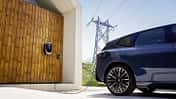 BMW iX3 an bidirektionign er angeschlossen Wallbox mit Stromnetz im Hintergrund, dargestellt als Beispiel für bidirektionales Laden und Vehicle-to-Grid.