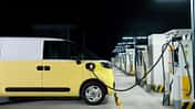 Elektrischer Transporter lädt nachts an einer Schnellladestation mit mehreren Ladepunkten.