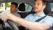 Junger Fahrschüler fährt unter Anleitung eines Fahrlehrers und bereitet sich auf den Pkw-Führerschein vor.