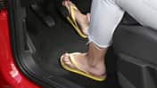 Person mit Flip-Flops bedient die Pedale eines Autos während der Fahrt.