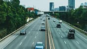 Mehrere Autos fahren auf einer mehrspurigen Stadtautobahn. Beim Nachfahren muss der Abstand für die Geschwindigkeitsmessung stimmen.